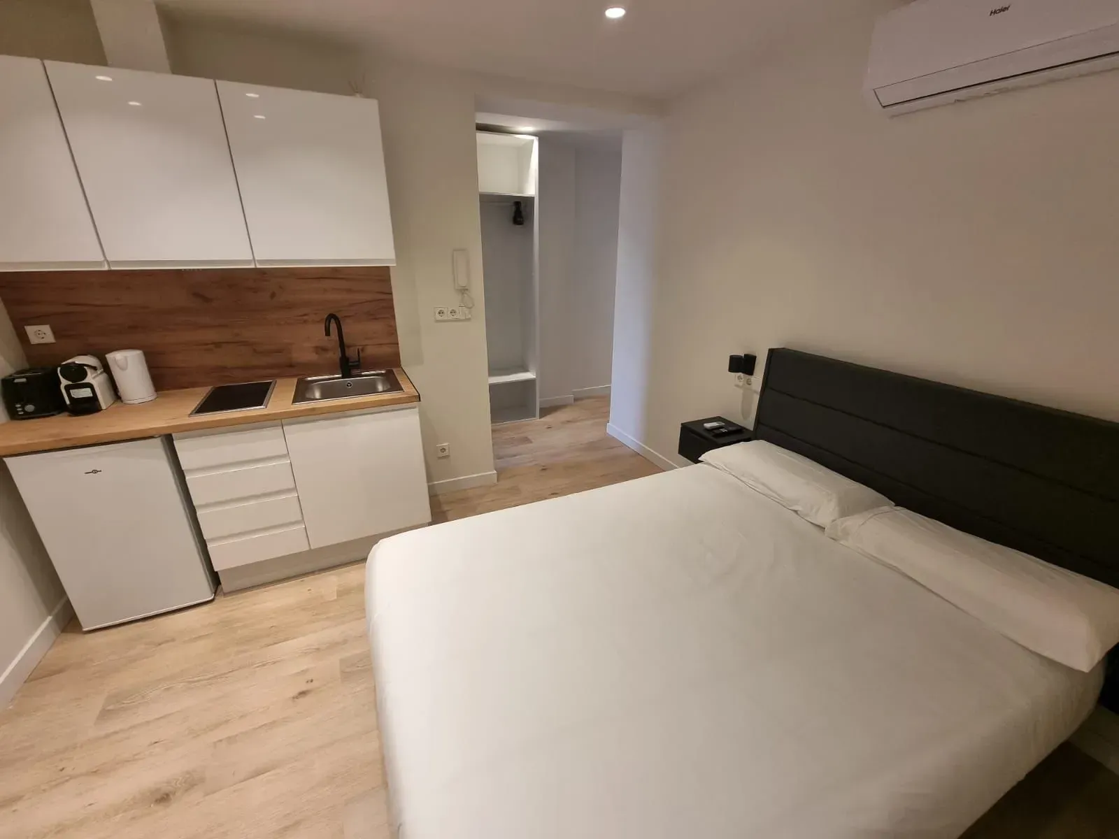 Un dormitorio con cama, cocina y lavabo.