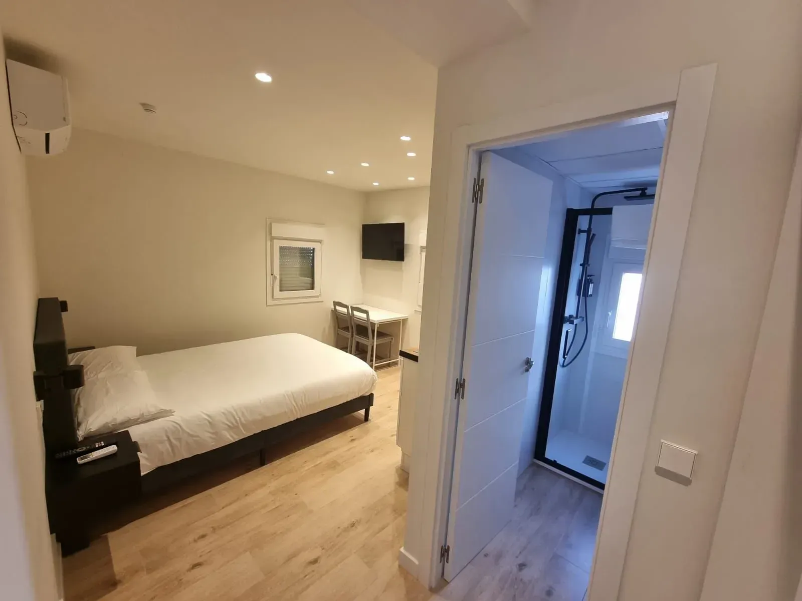 Un dormitorio con una cama, escritorio, sillas y una puerta que conduce a un baño.