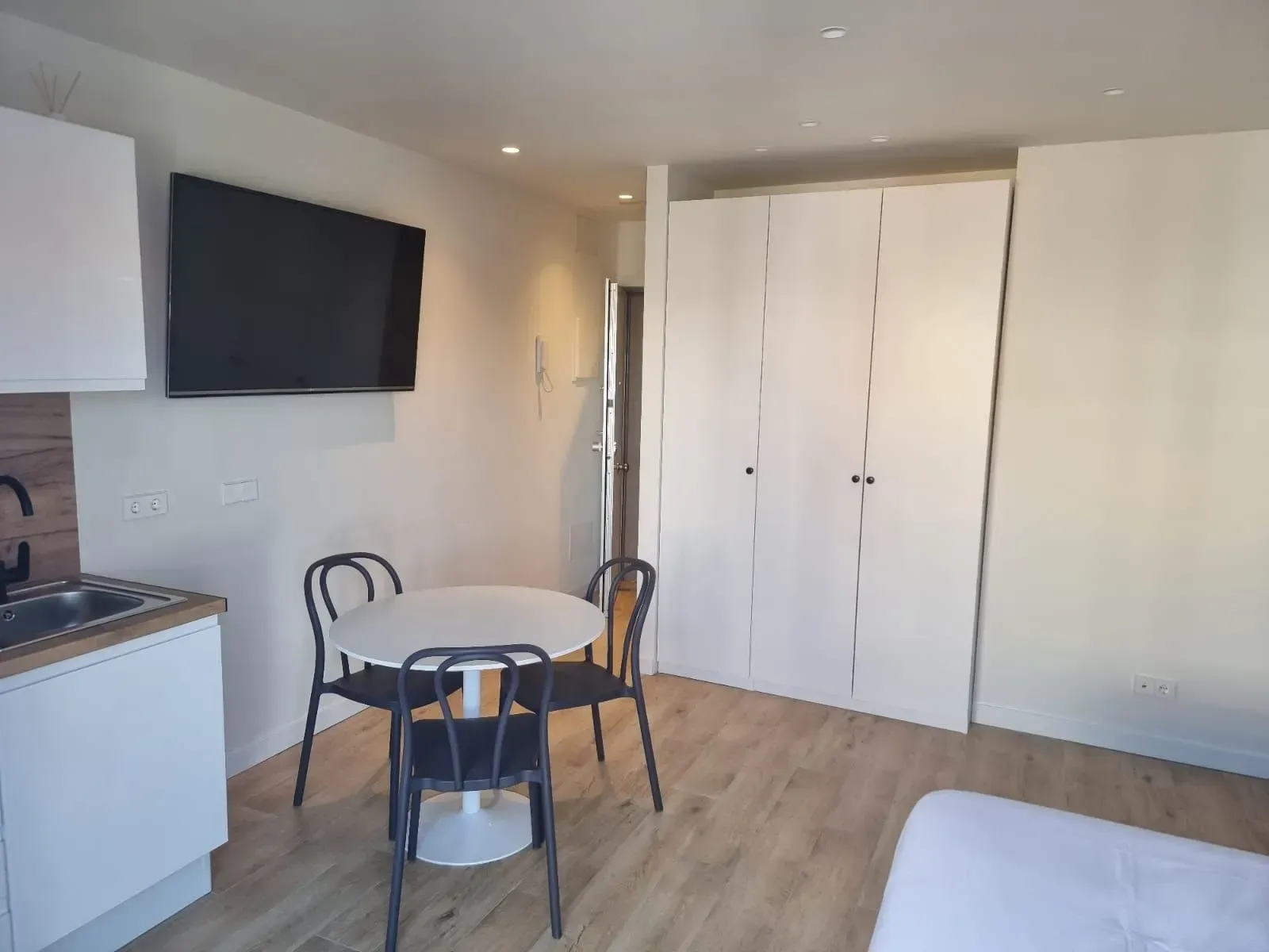 Una cocina con mesa y sillas y un televisor de pantalla plana.