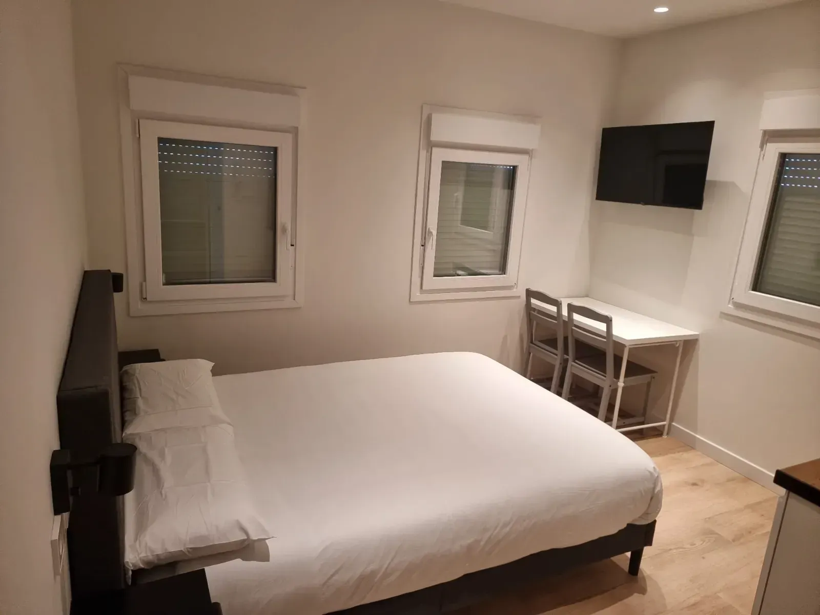 Un dormitorio con una cama, un escritorio, sillas y un televisor.