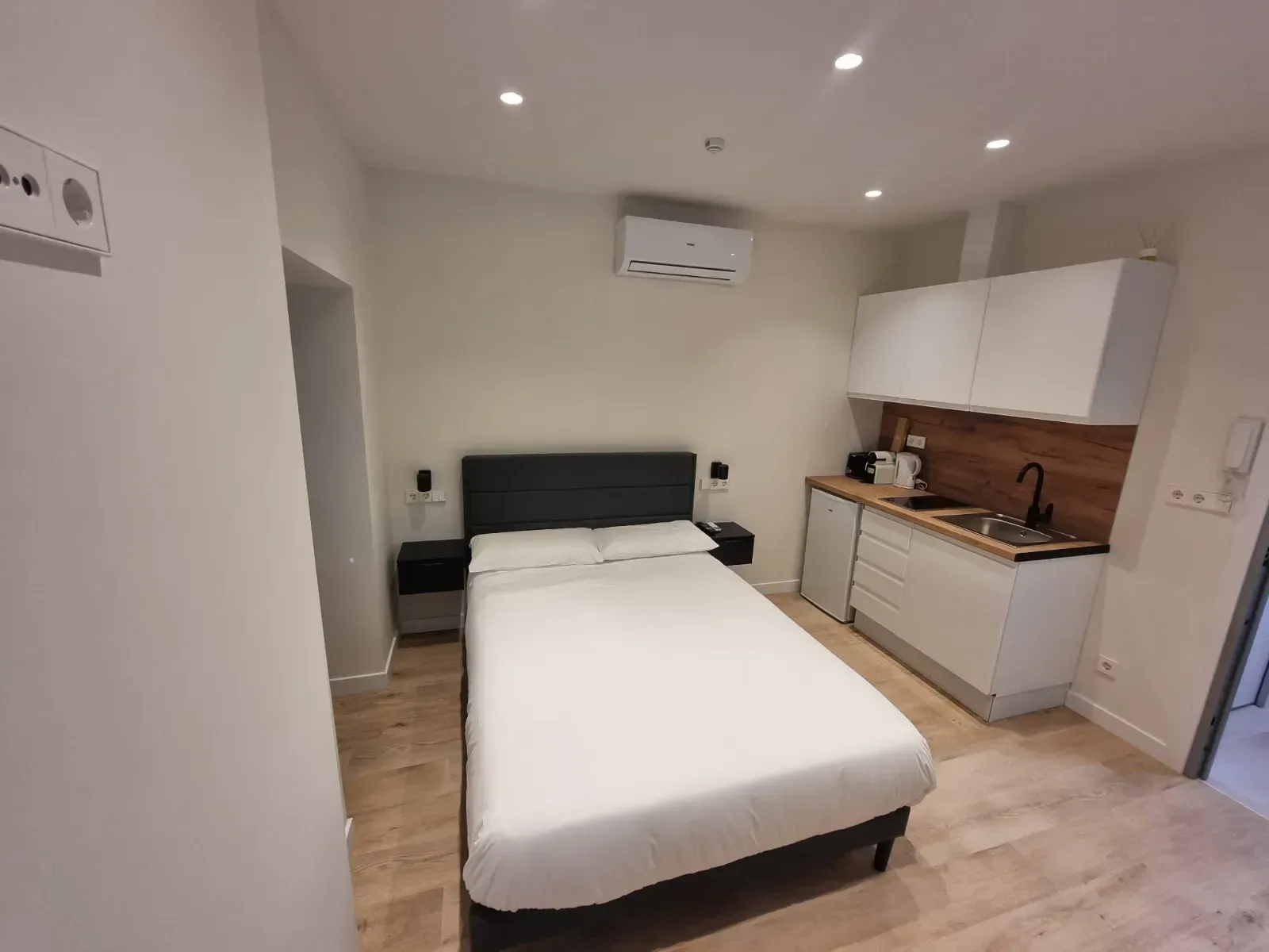 Un dormitorio con una cama y una cocina en él.