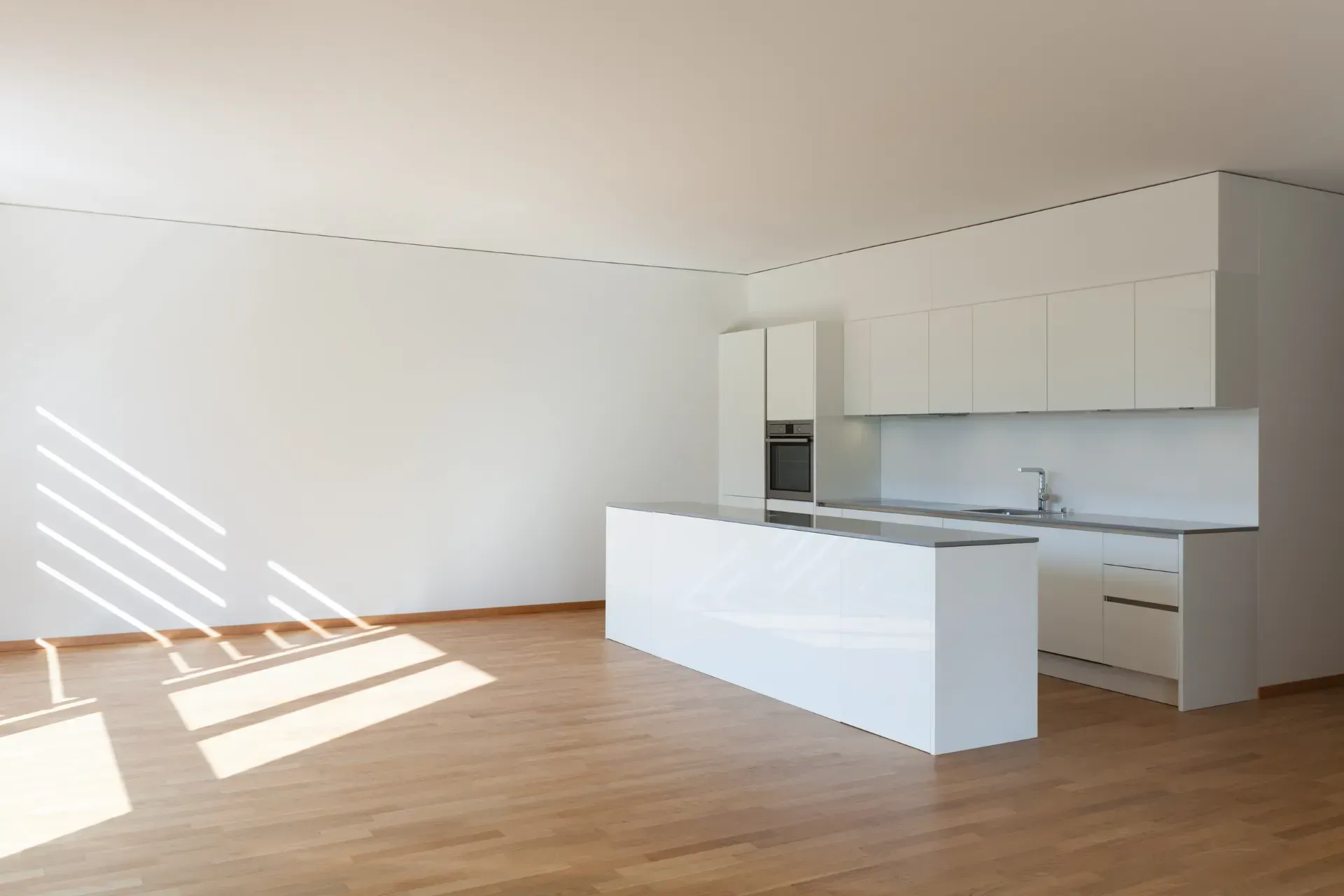 Una cocina vacía con gabinetes blancos y piso de madera.