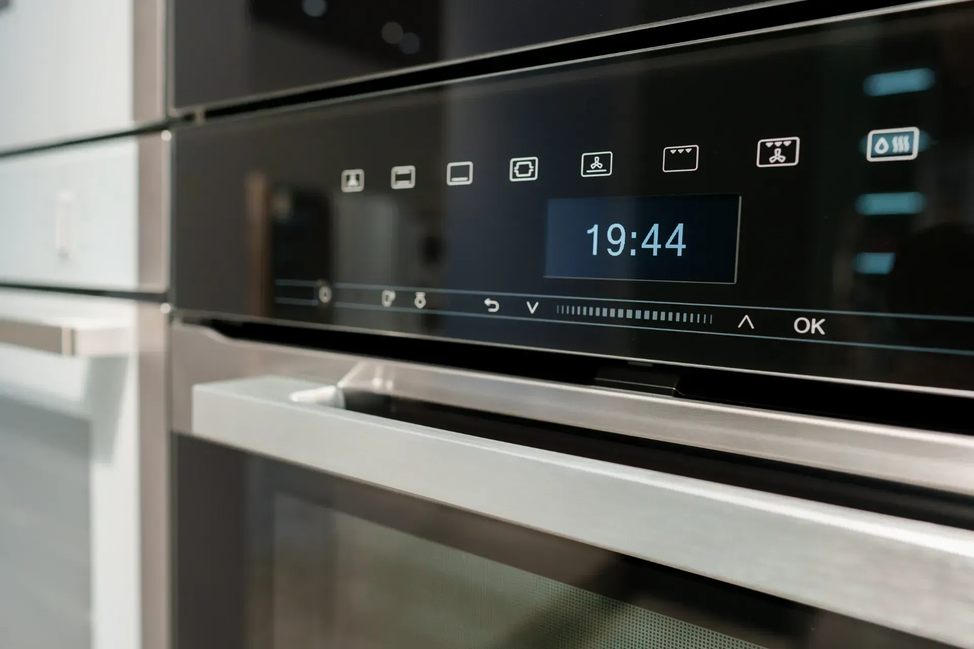 Un primer plano de un horno de acero inoxidable que muestra la hora como 19:44