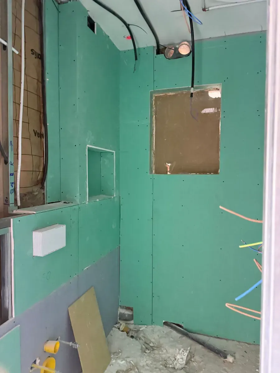 Un baño en construcción con paredes verdes y una ventana.