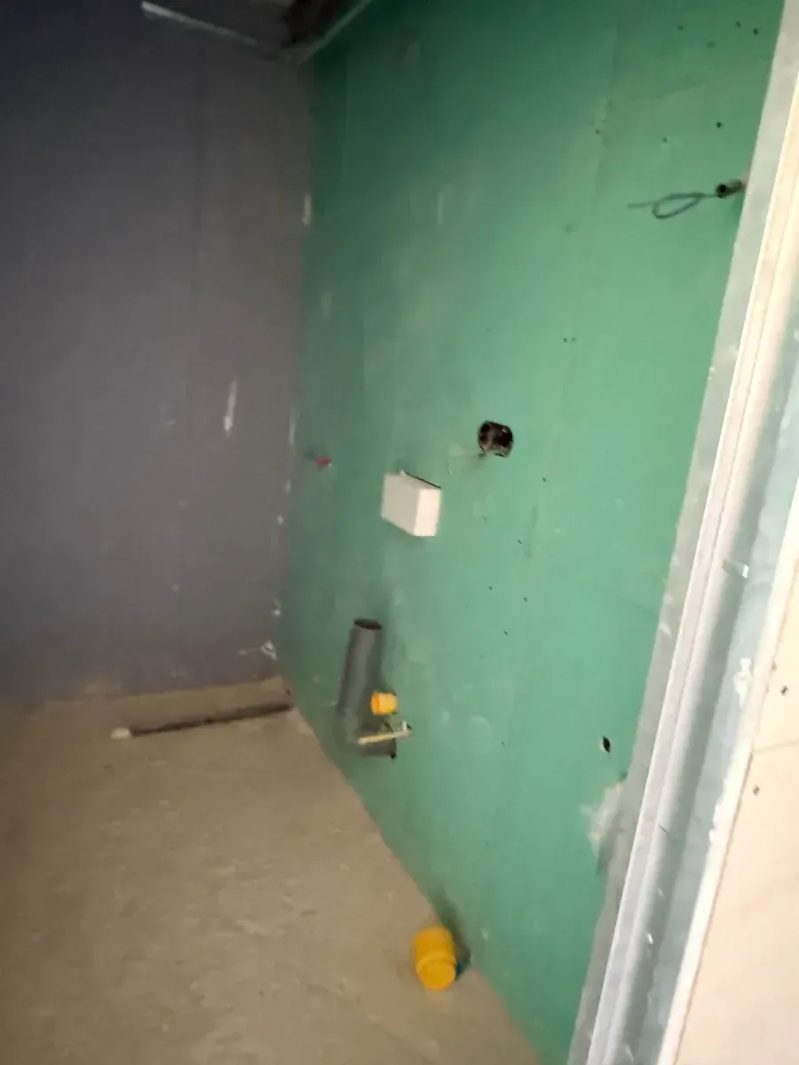 Una habitación con una pared verde y una pelota amarilla en el suelo.