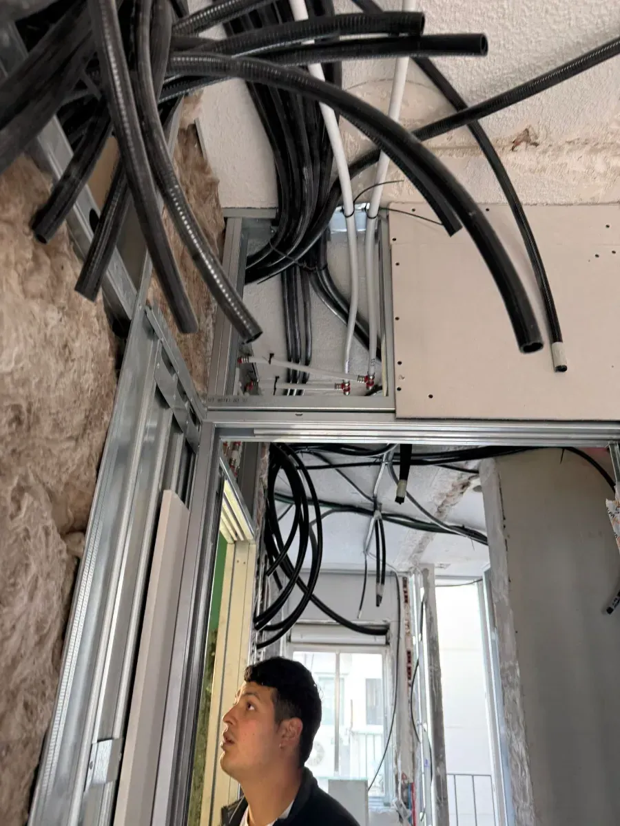 Un hombre mira hacia arriba y ve un montón de cables que cuelgan del techo.