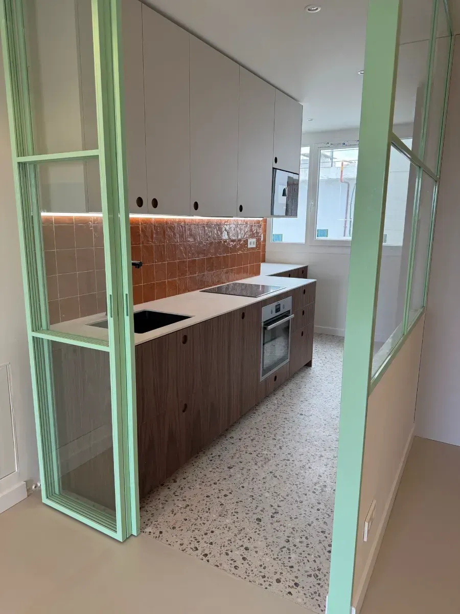 Una cocina con una puerta corrediza de vidrio verde y gabinetes de madera.