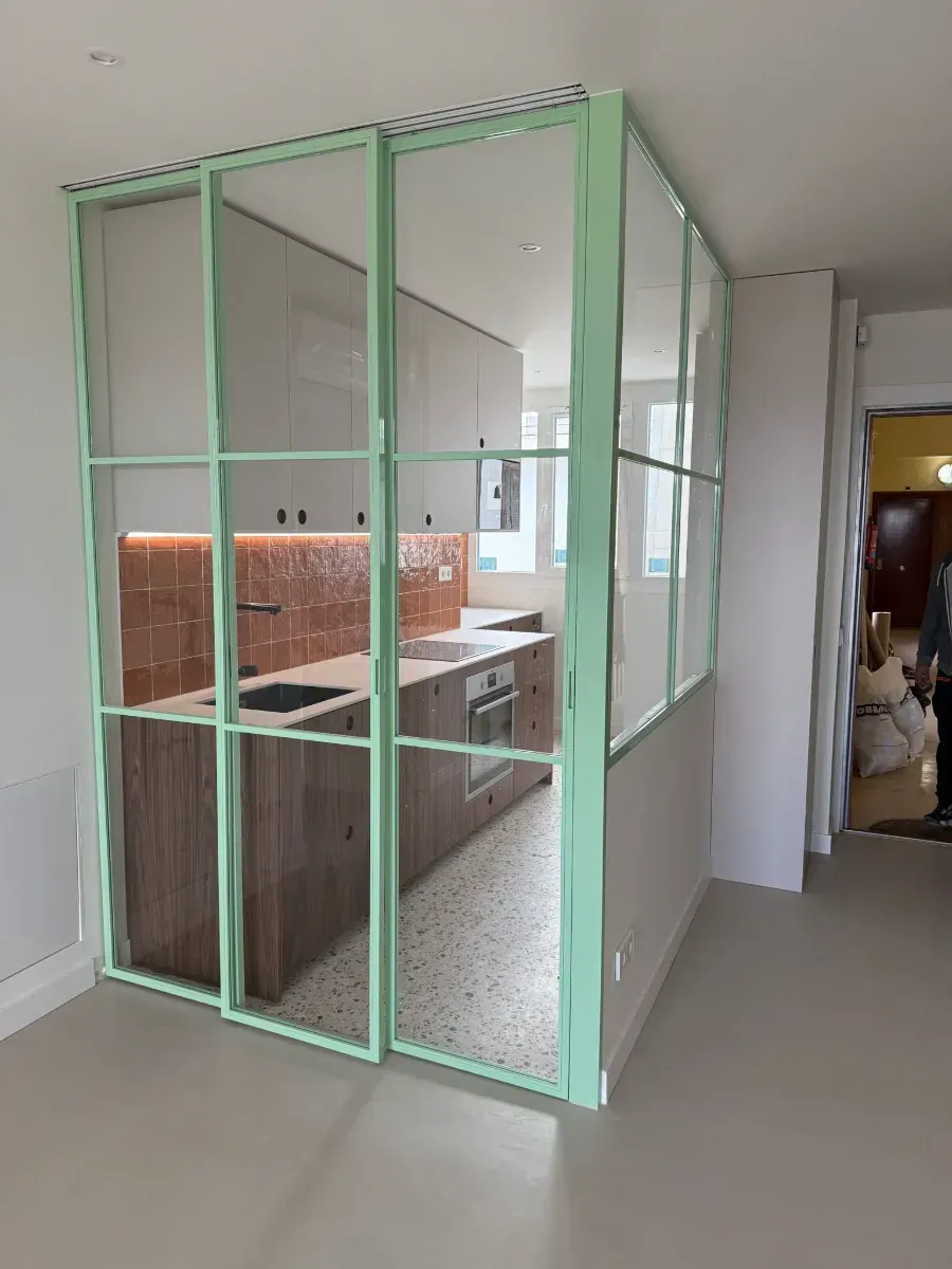 Una cocina con una partición verde entre la cocina y la sala de estar.