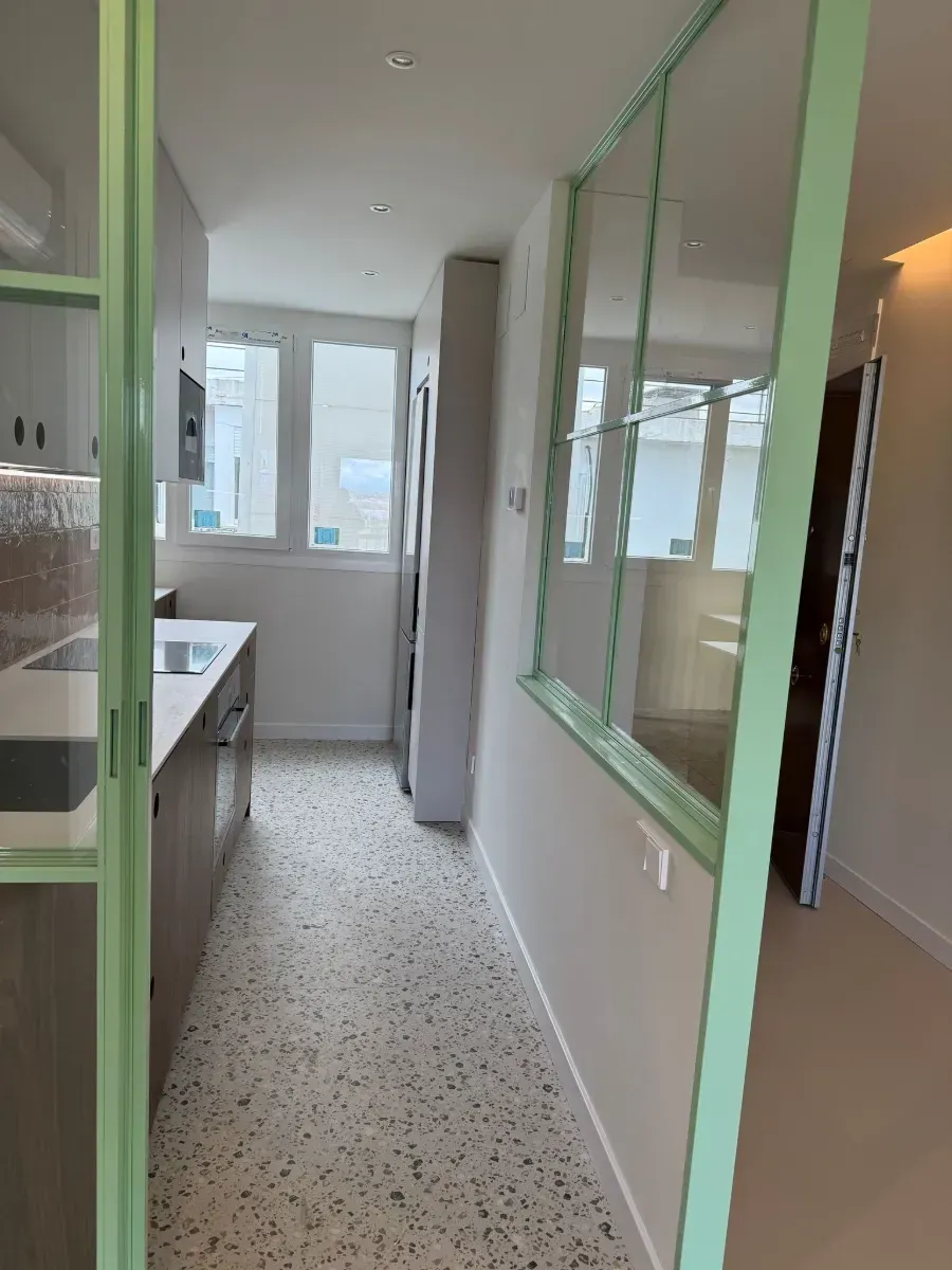 Un largo pasillo que conduce a una cocina con una puerta verde.