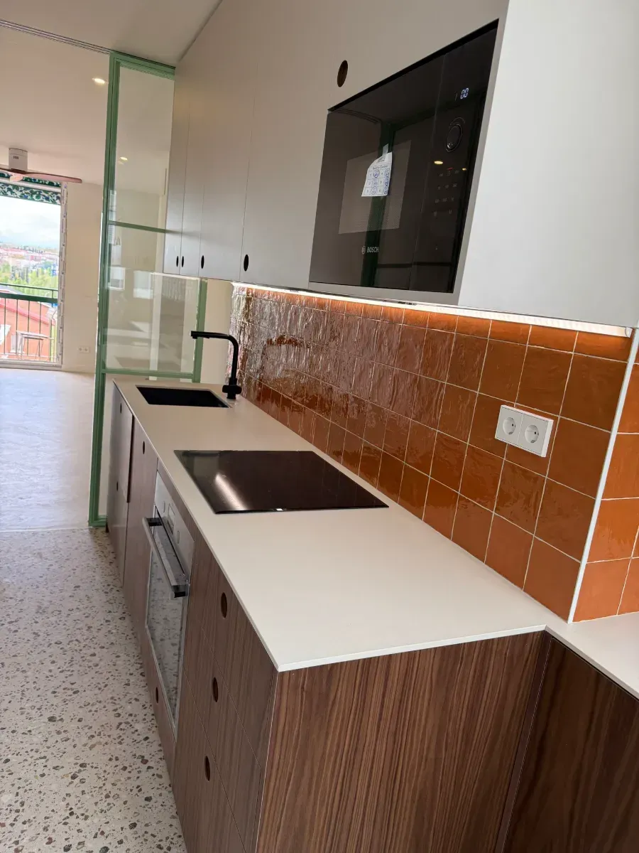 Una cocina con gabinetes de madera y encimeras blancas.