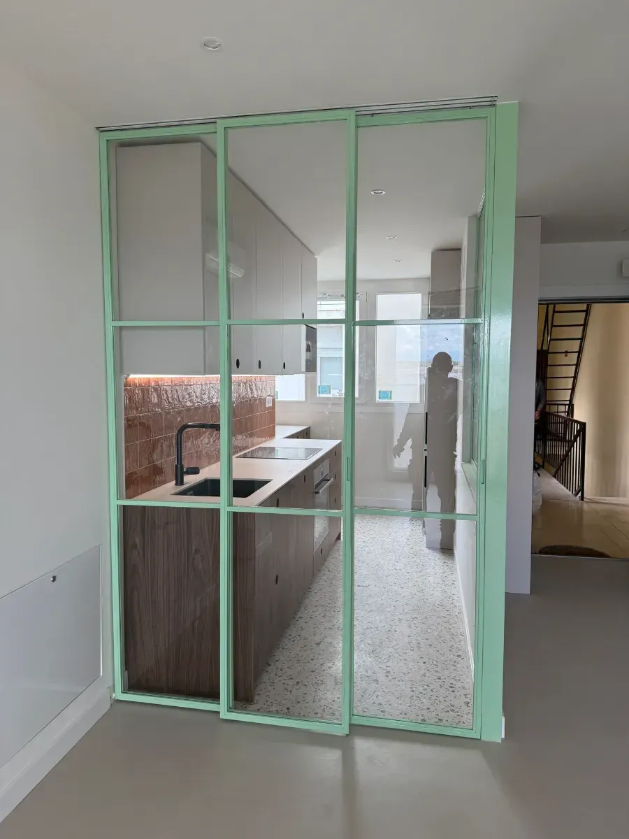 Una cocina con una puerta corrediza de vidrio verde entre la cocina y la sala de estar.