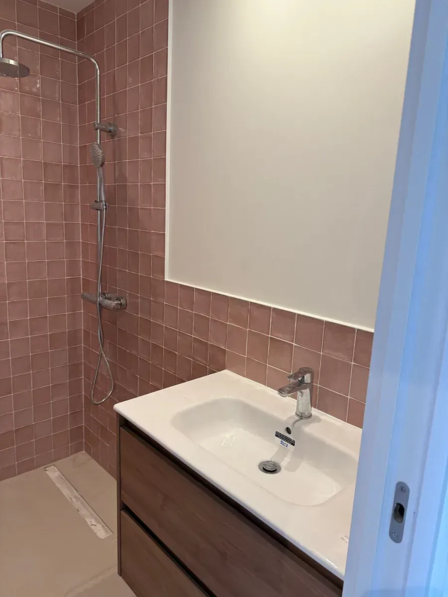 Un baño con lavabo, ducha y espejo.