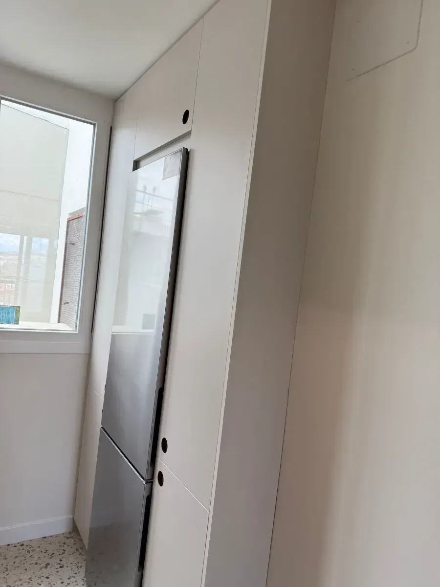 Una cocina con nevera y ventana.