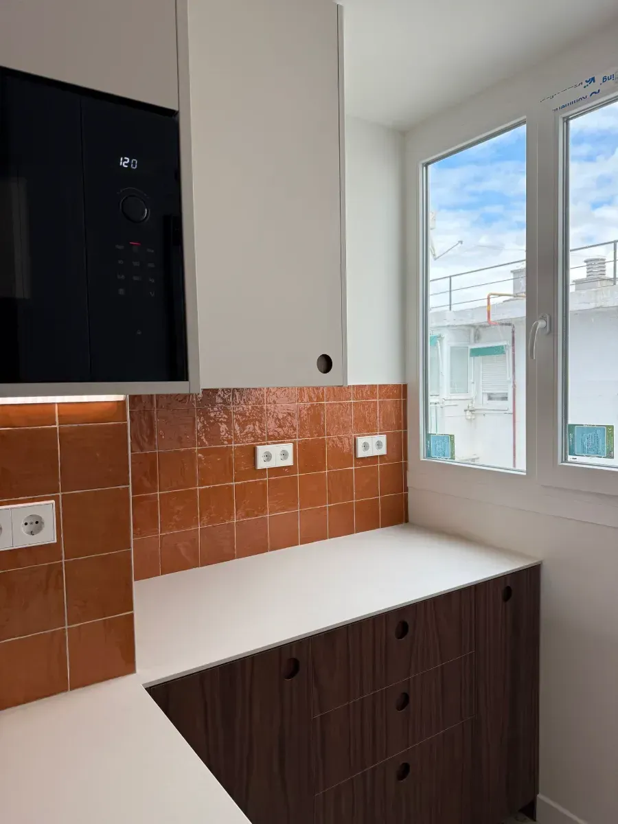 Una cocina con un microondas encima de la encimera y una ventana.