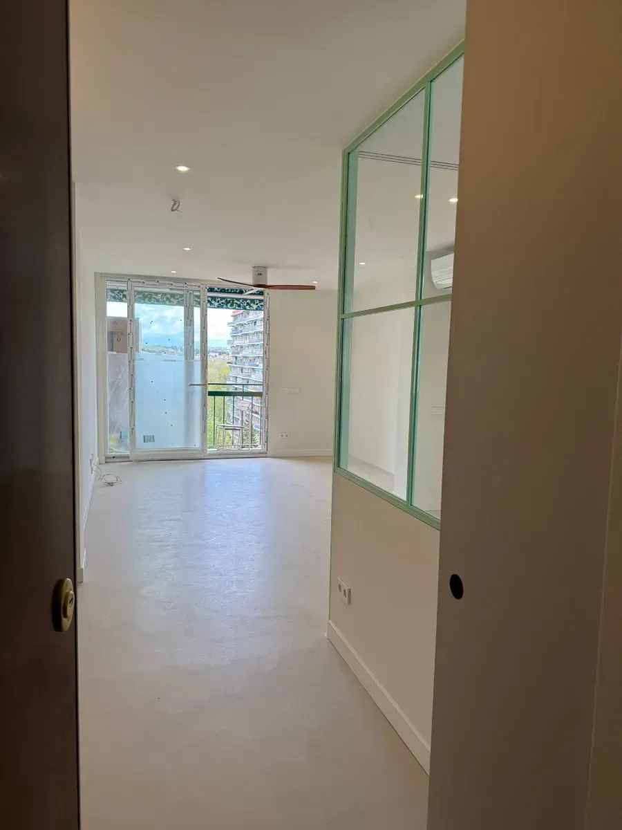 Una gran habitación vacía con muchas ventanas y un ventilador de techo.