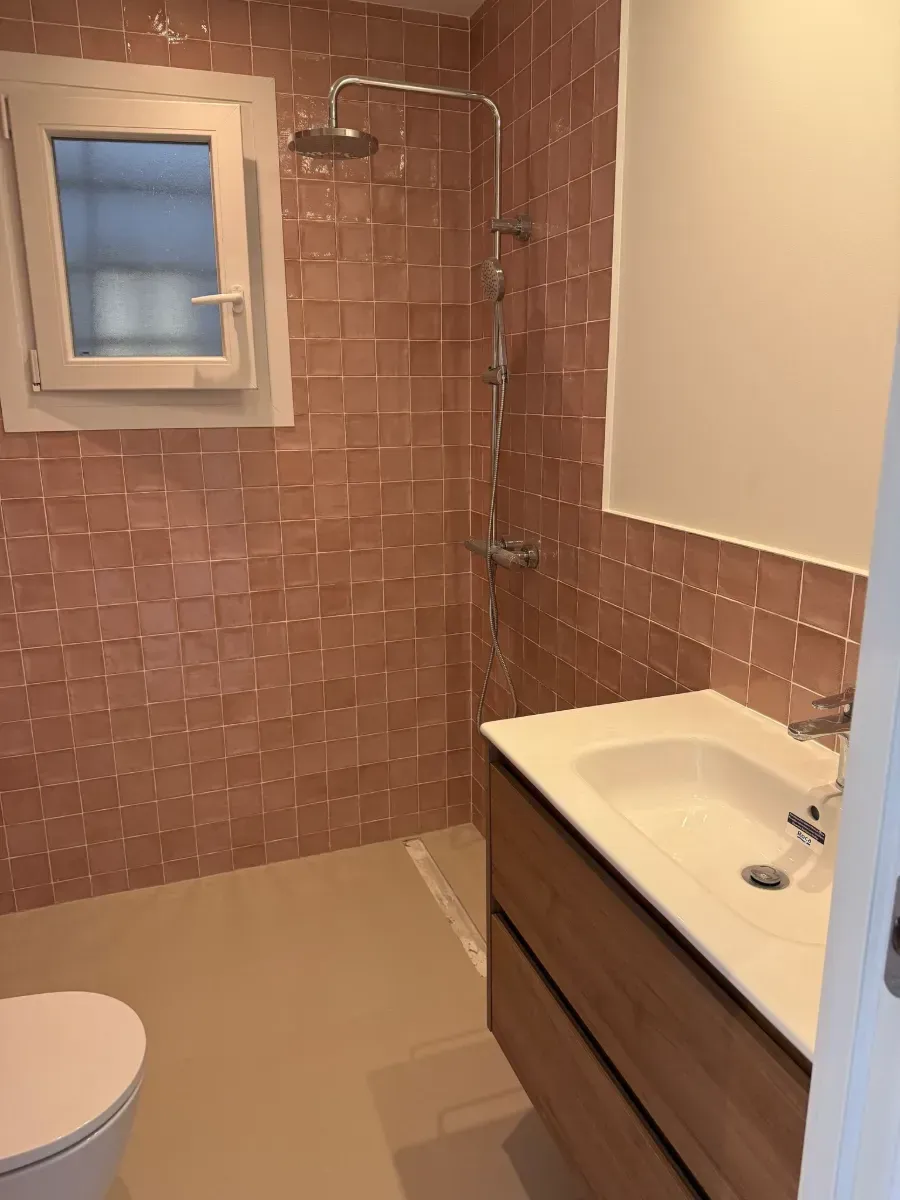 Un baño con inodoro, lavabo, ducha y ventana.