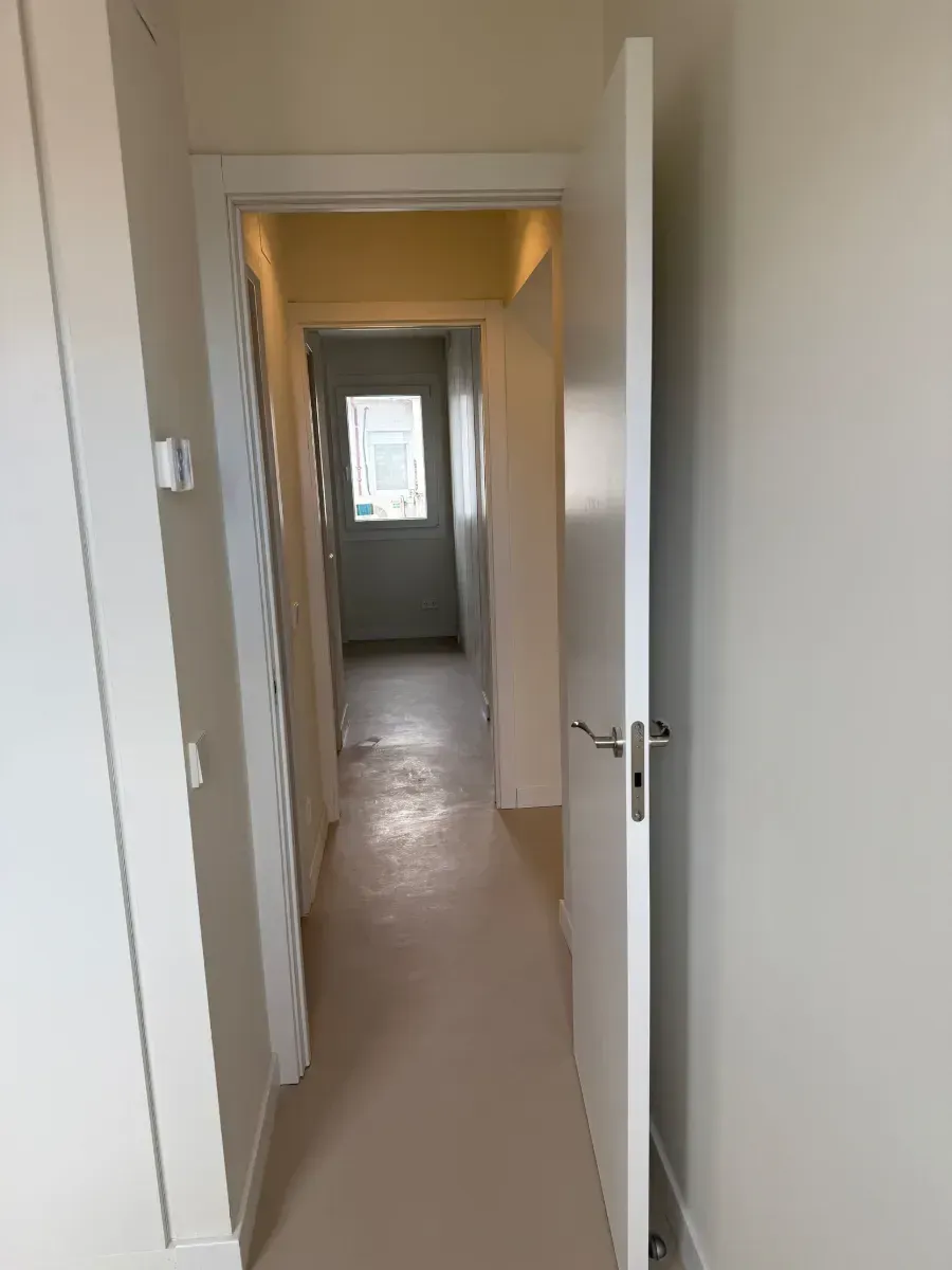 Un pasillo con una puerta abierta y una ventana.