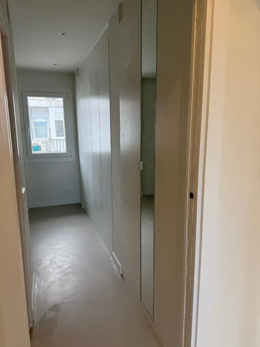 Un largo pasillo con un espejo en la pared y una ventana.