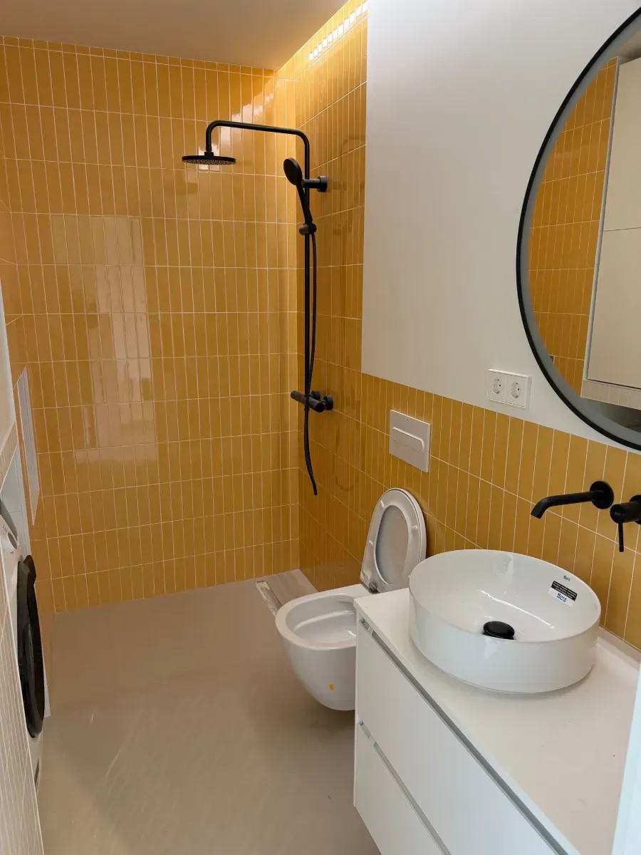 Un baño con inodoro, lavabo, ducha y espejo.