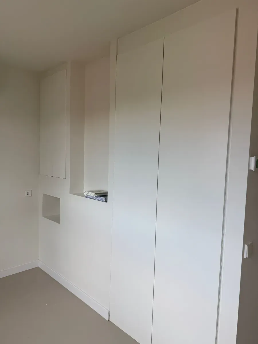 Una habitación con muchas paredes blancas y una puerta.