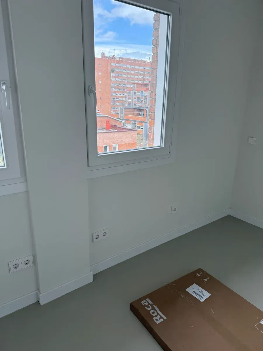 Una habitación vacía con una ventana y una caja en el suelo.