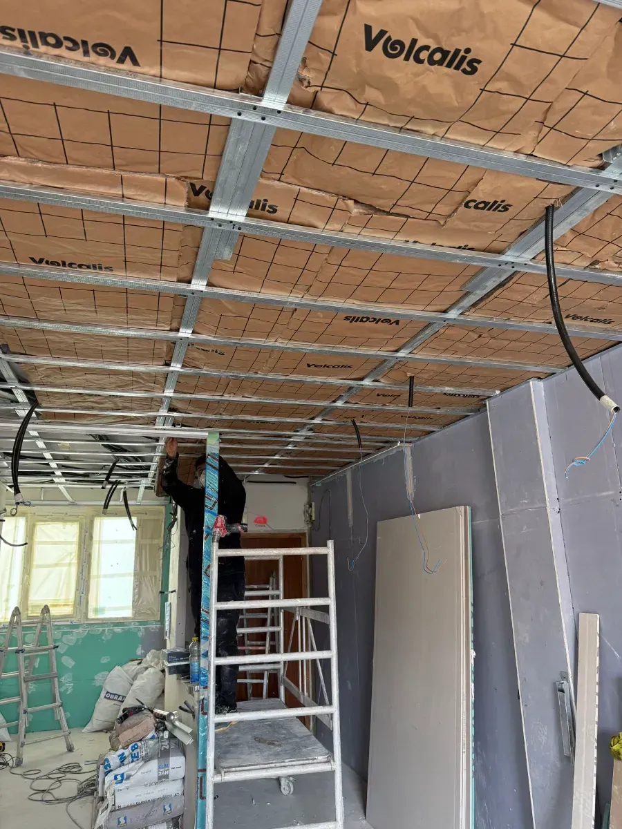 Un hombre está trabajando en el techo de una habitación.