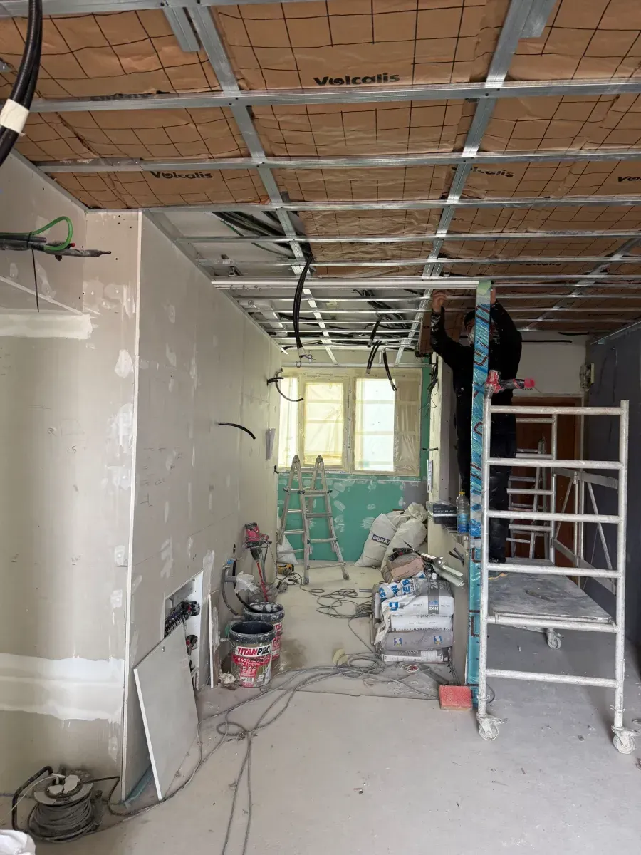 Un hombre está de pie sobre un andamio en una habitación en construcción.