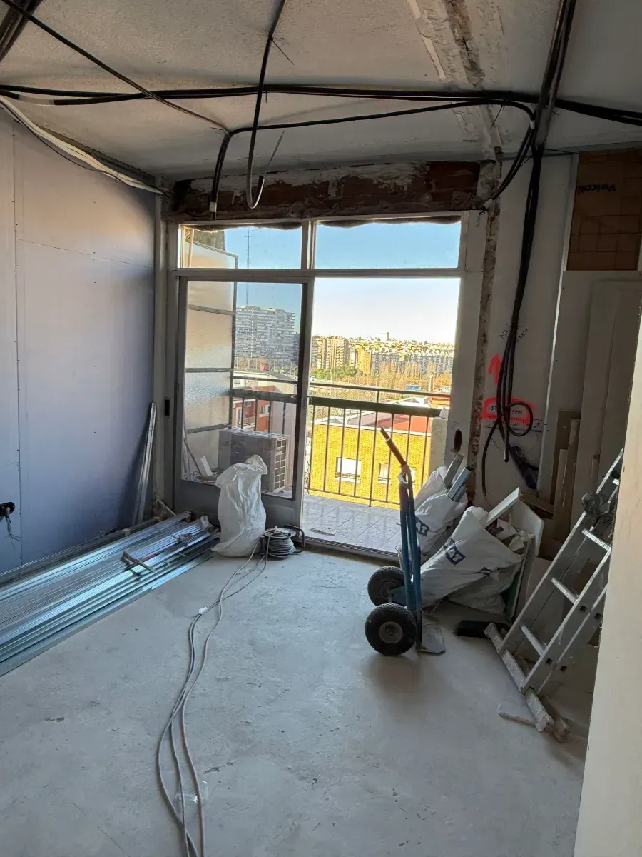 Una habitación en construcción con una escalera y una carretilla manual.