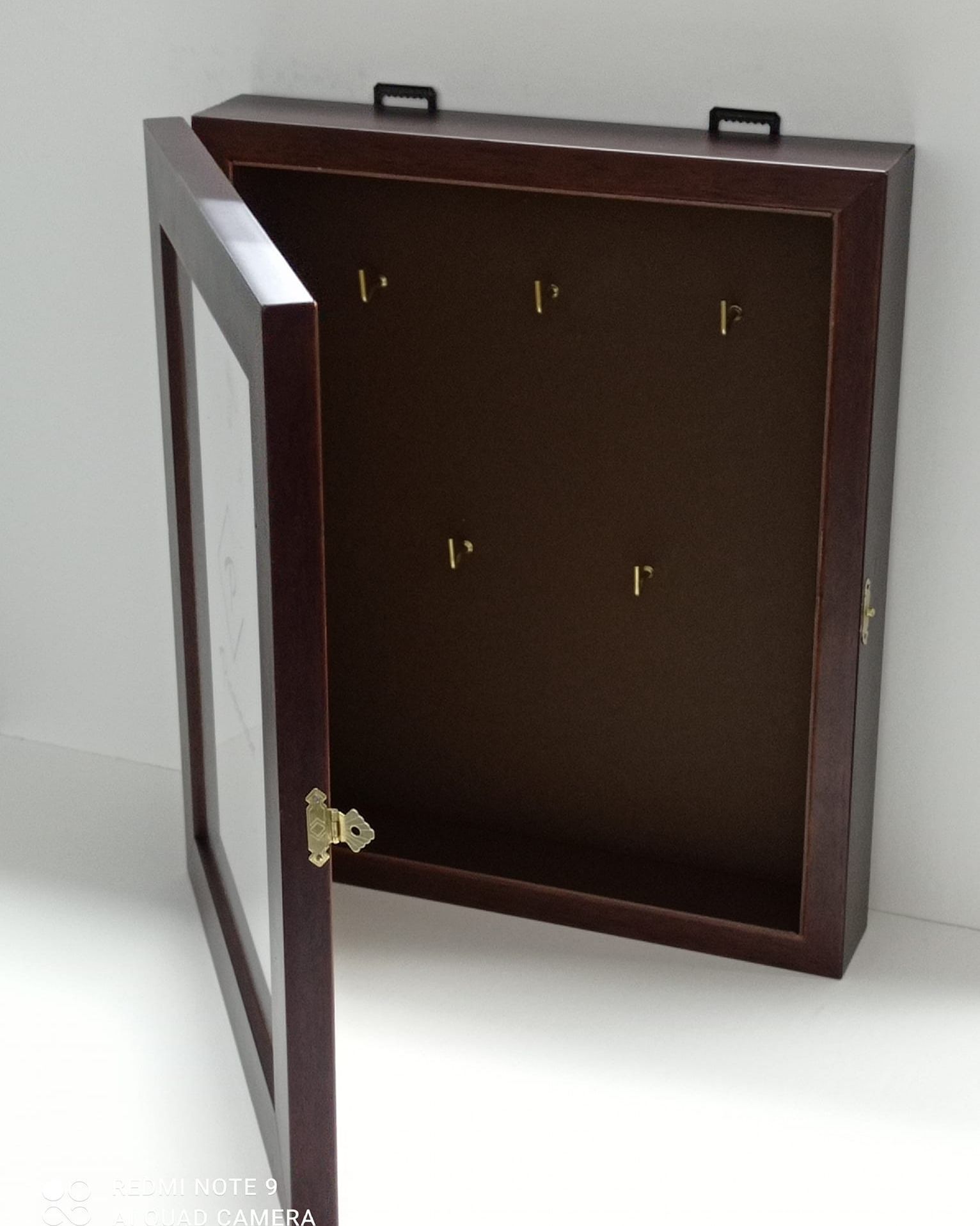 Una caja de madera con una puerta de cristal está abierta.