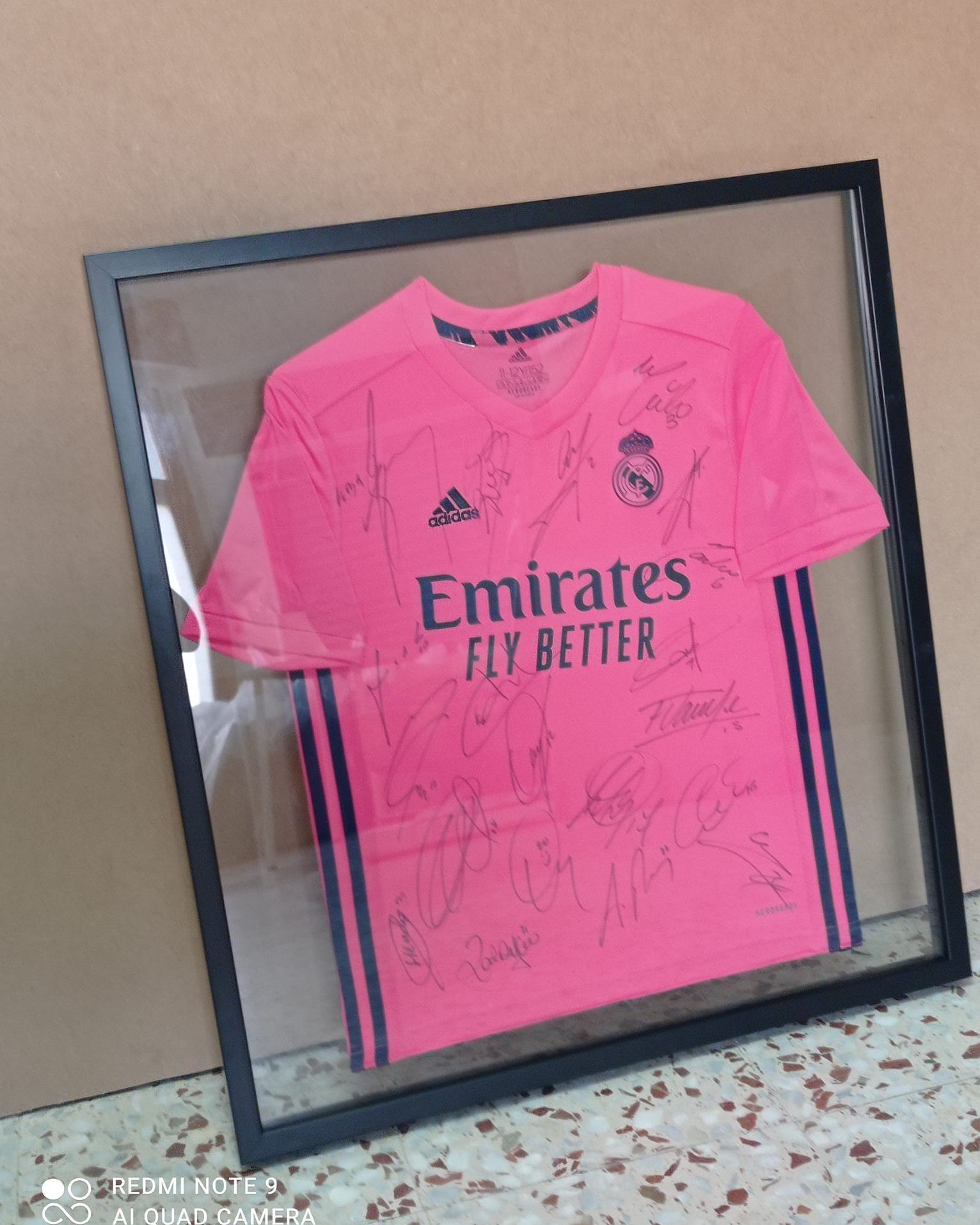 Una camiseta rosa de Emirates Fly Better en un marco de cristal