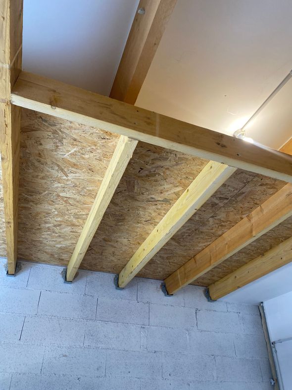 Solives de plafond en bois et sous-plancher en OSB vus d'en bas dans un garage ou une pièce non aménagée