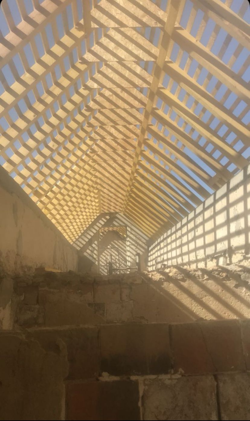 Vue ensoleillée sur un escalier de pierre abrupt sous un toit en treillis projetant des ombres diagonales