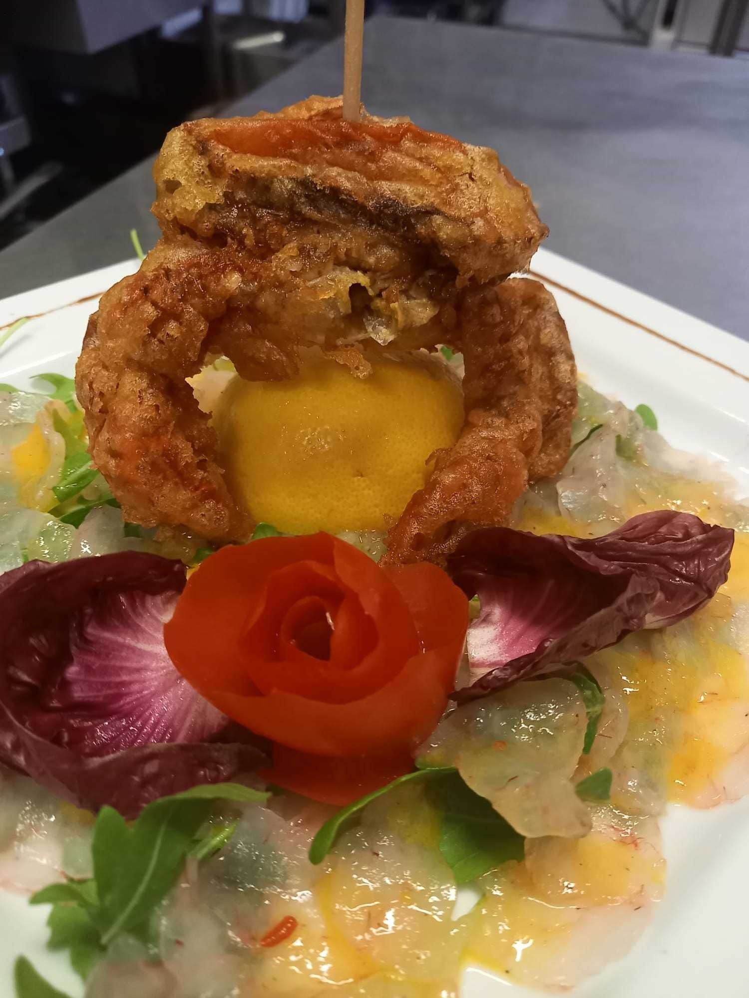 Un plato de comida con un camarón frito encima