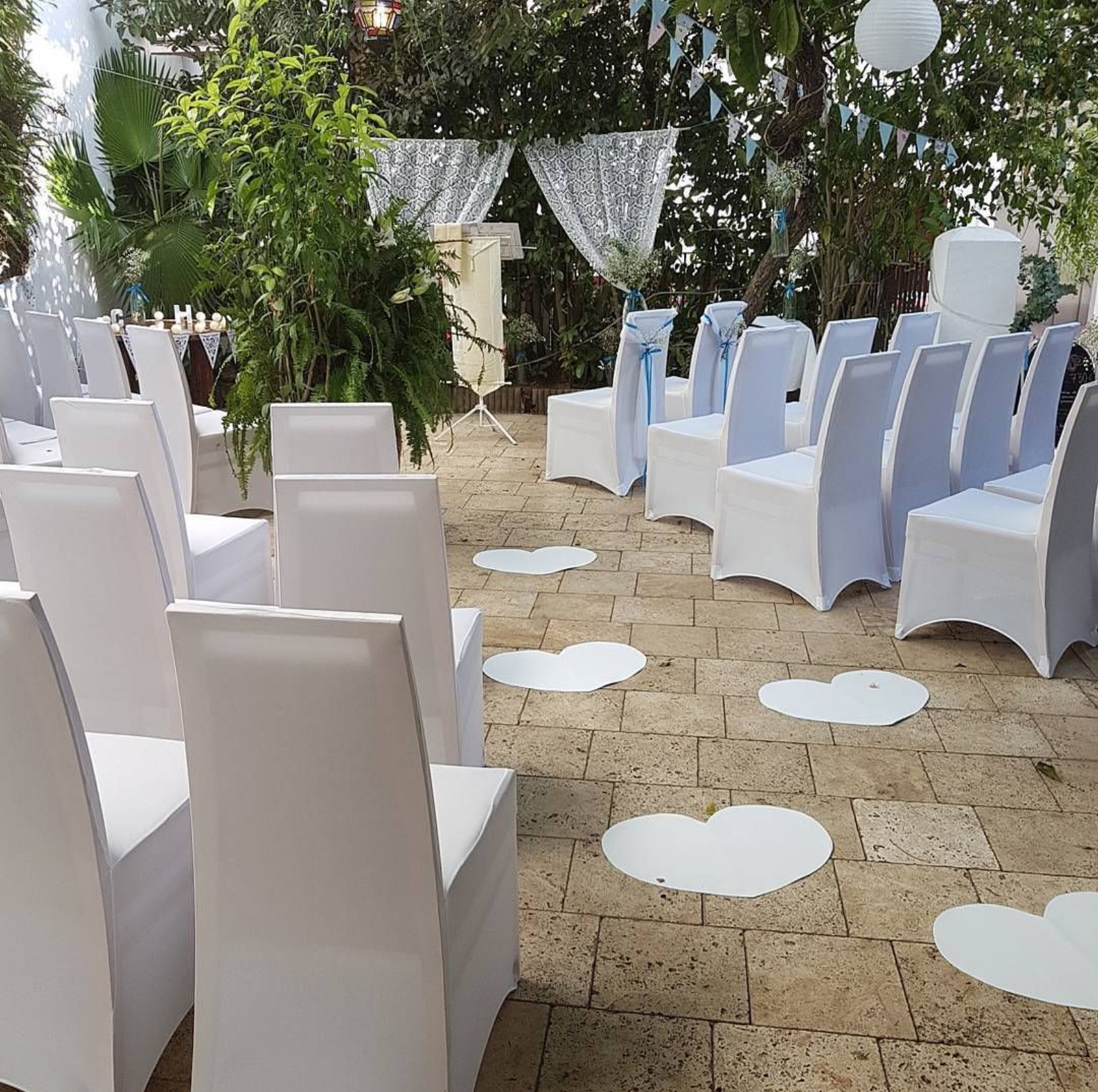 Una fila de sillas blancas con corazones blancos en el suelo.