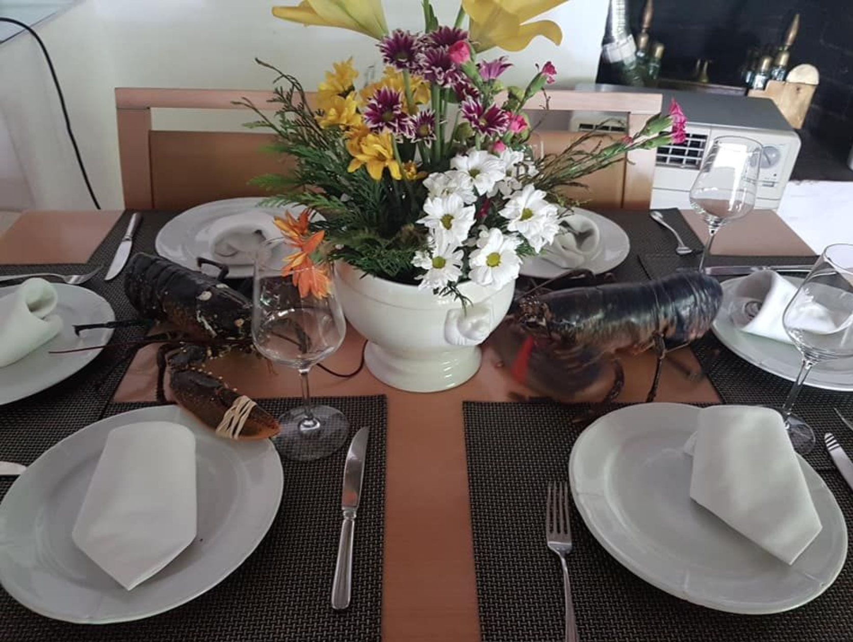Una mesa puesta con platos, cubiertos y un jarrón de flores.