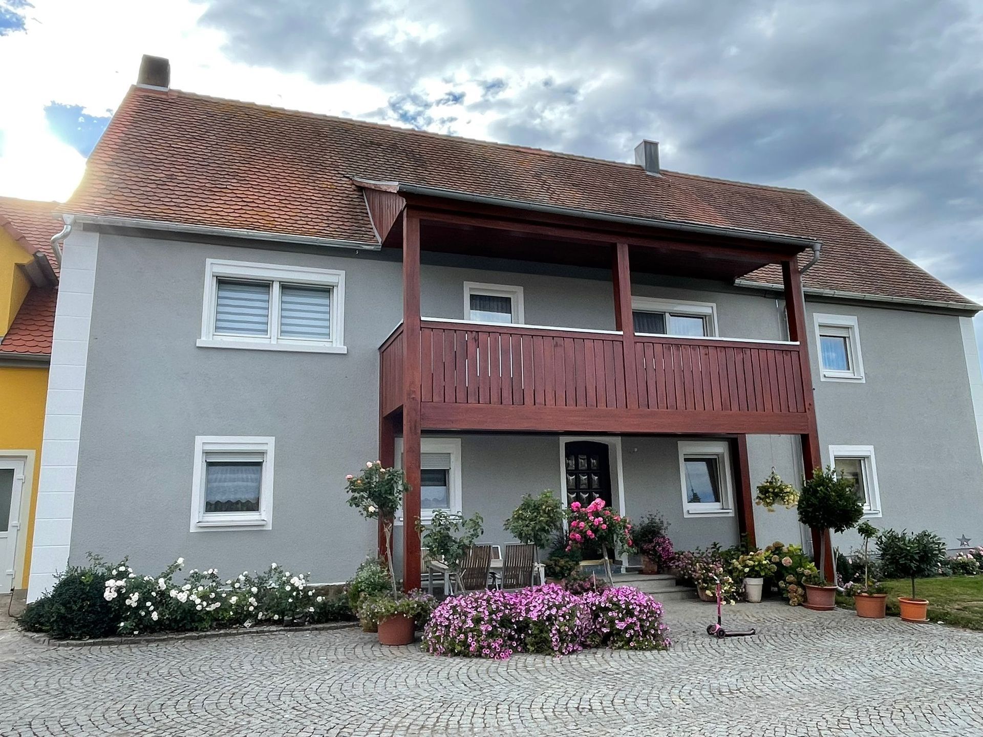 Graue Fassade mit hellen Ecken und Holzbalkon