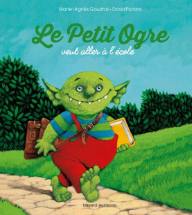 Un ogre vert souriant marche sur un chemin de pierre, portant un cartable et un livre sous un ciel bleu, texte du titre au-dessus.
