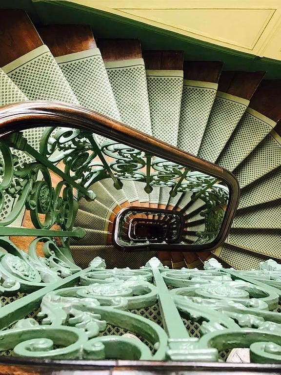 Escalier d'immeuble ancien avec rampe en fer forgé travaillé et peint en vert 
