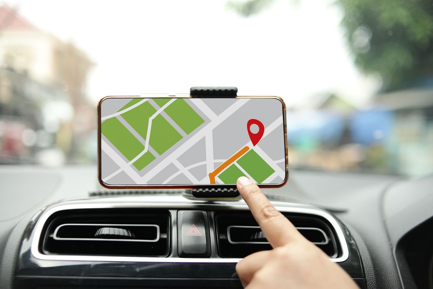 Un smartphone avec système de navigation GPS fixé sur le tableau de bord d'une voiture, la main pointant vers la carte de l'itinéraire.
