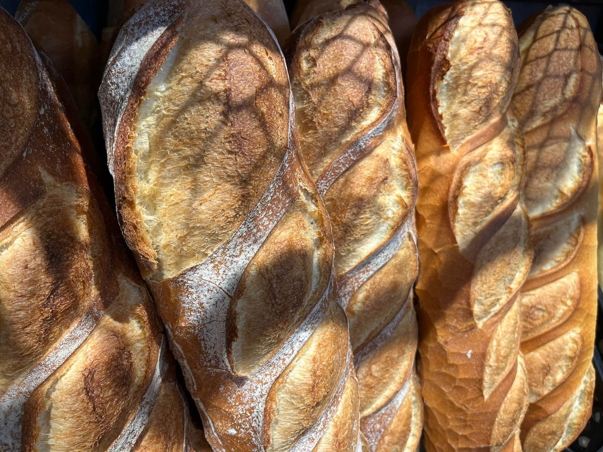Des miches de pain tressé croustillantes à la croûte dorée, empilées les unes sur les autres.