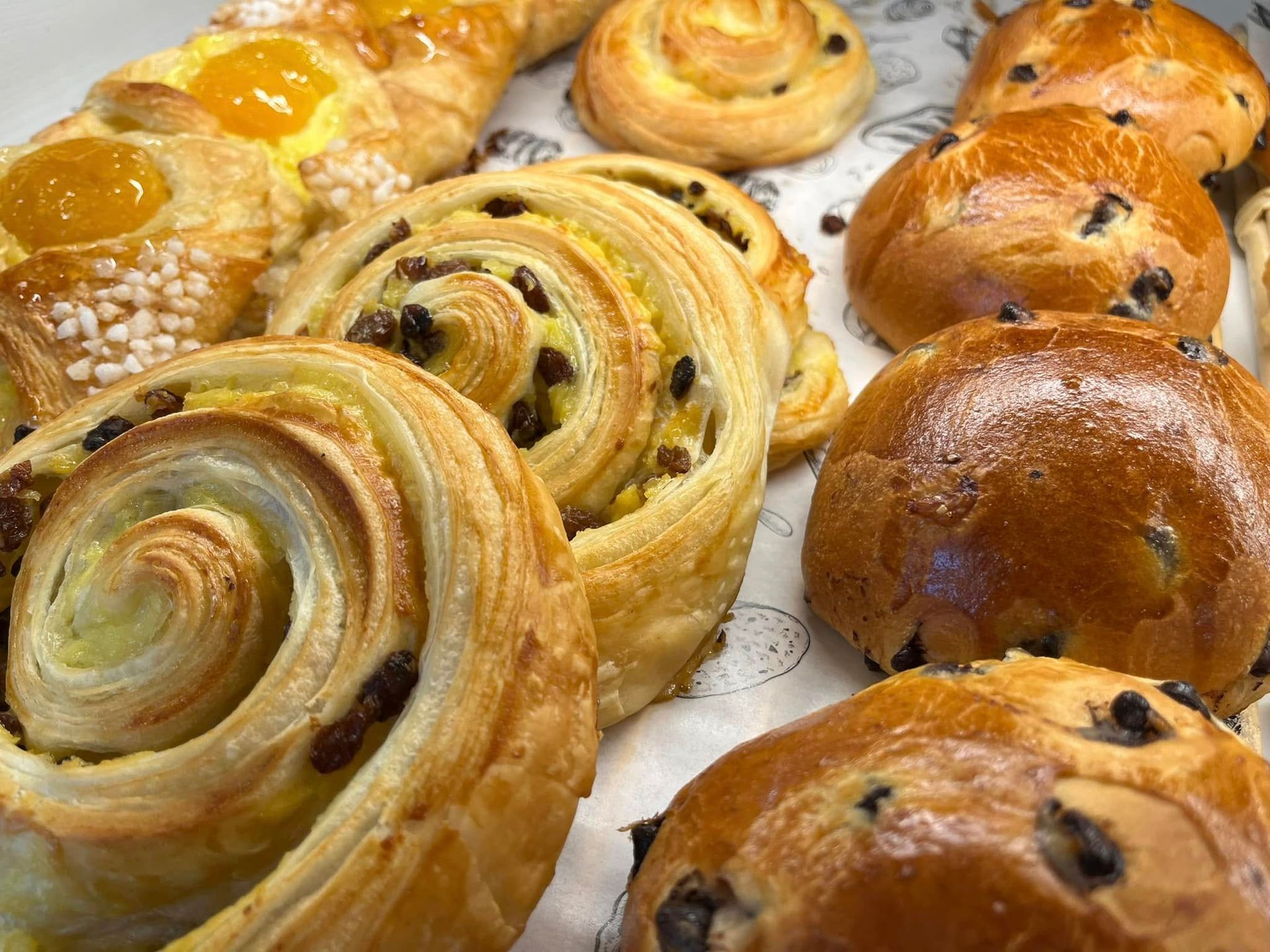 Assortiment de viennoiseries glacées et de petits pains au chocolat sur un plateau, dorés et fraîchement sortis du four.