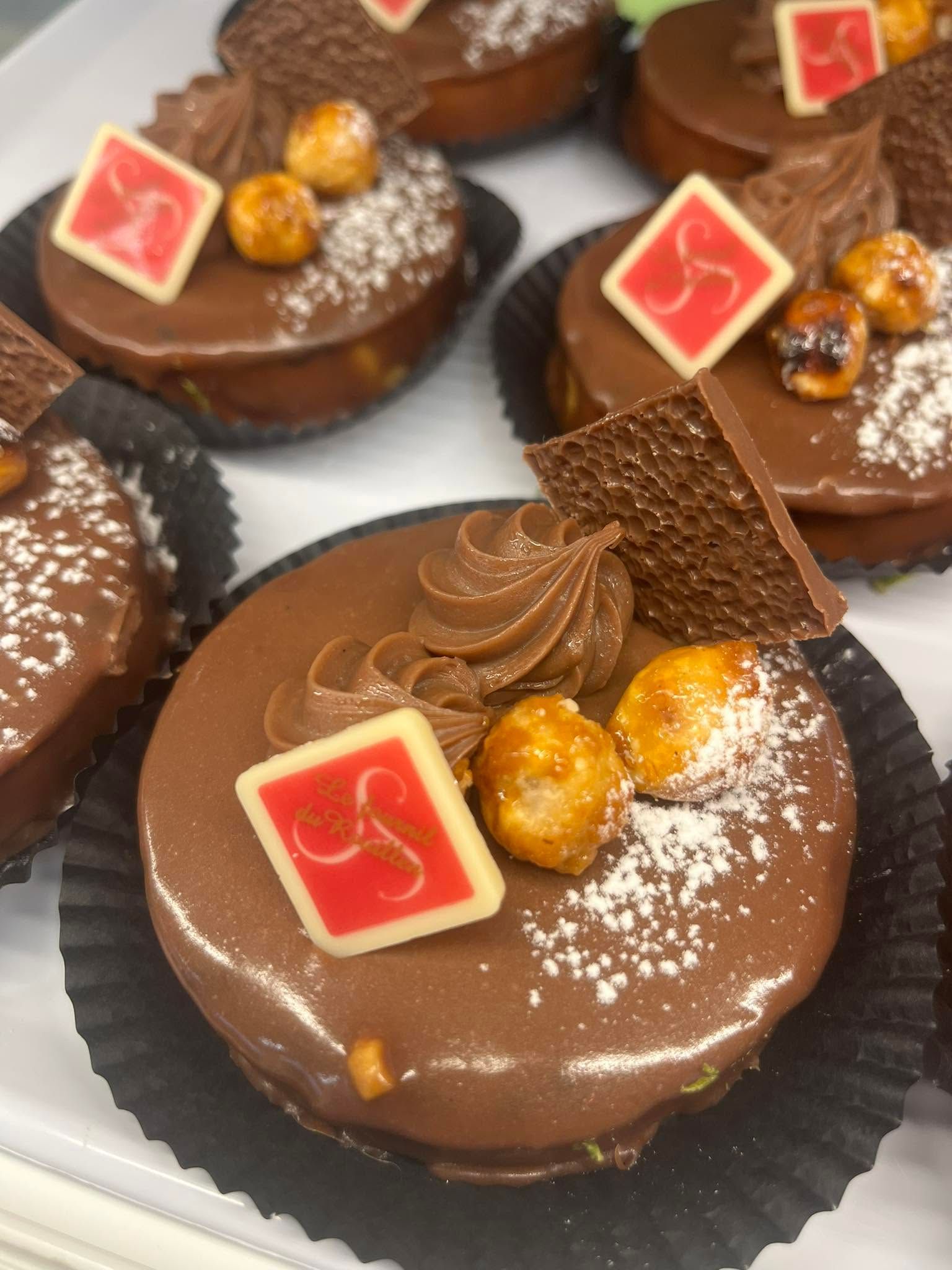 Pâtisseries à la mousse au chocolat garnies de crème fouettée, de dragées dorées et de carrés rouges.