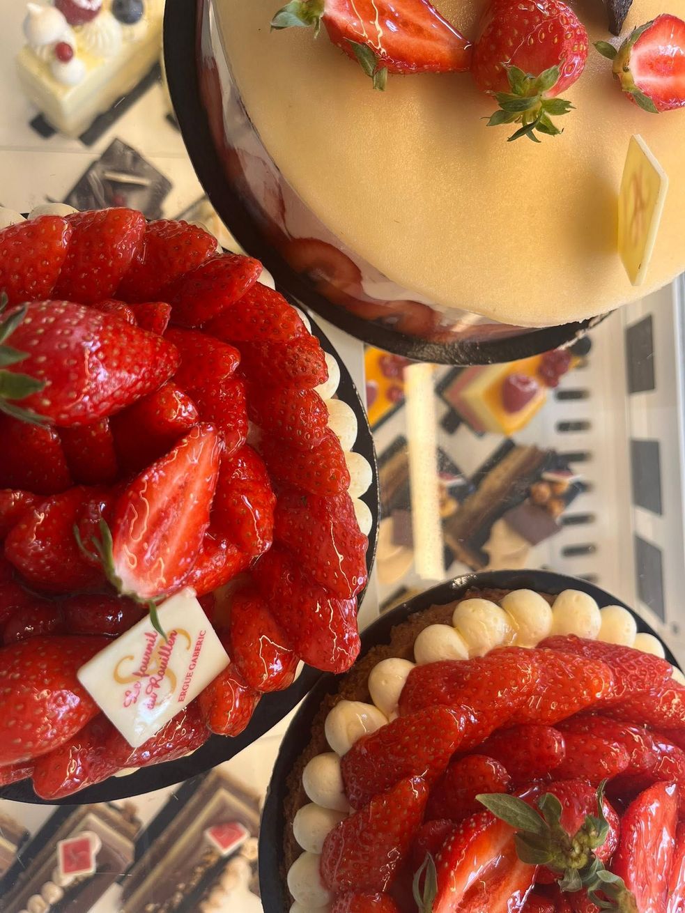 Tartes aux fruits assortis avec fraises et crème sur une table de présentation de boulangerie.