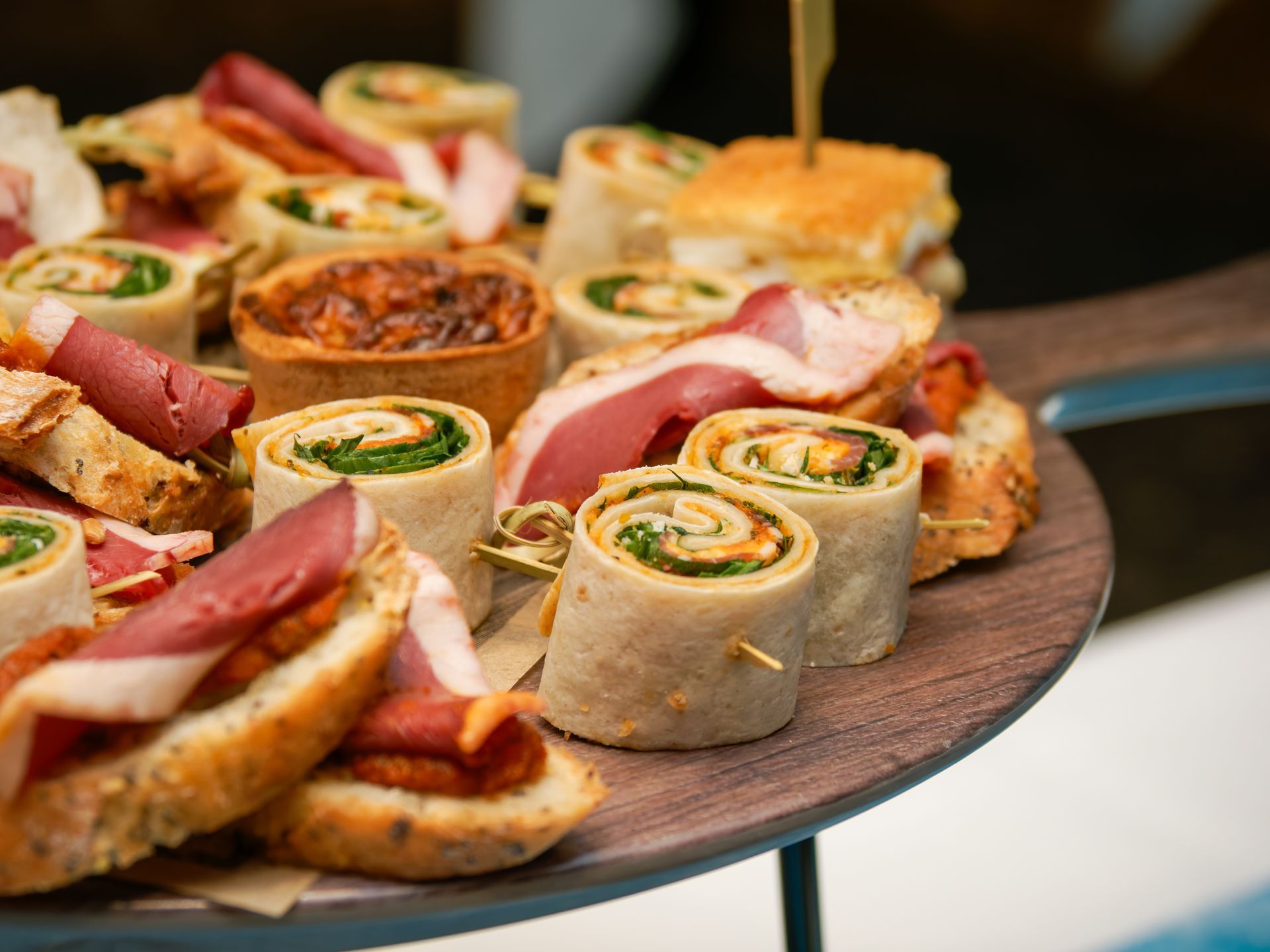 Assortiment de petits sandwichs et de wraps disposés sur un plateau de service à une table de traiteur.