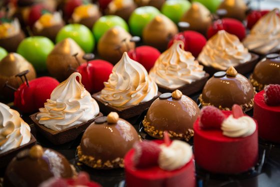 Assortiment de minipâtisseries et de chocolats colorés disposés sur un plateau, garnis de crème fouettée et de décorations.