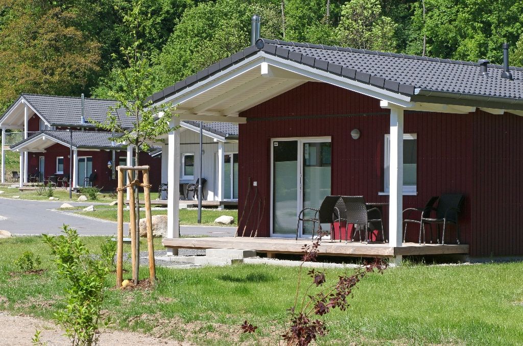 Rote Häuser im Landhausstil mit Veranden in einer ländlichen, grasbewachsenen Umgebung unter Bäumen