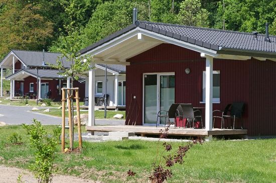 Zwei kleine rote Hütten mit Veranden neben einer Wiese und Bäumen