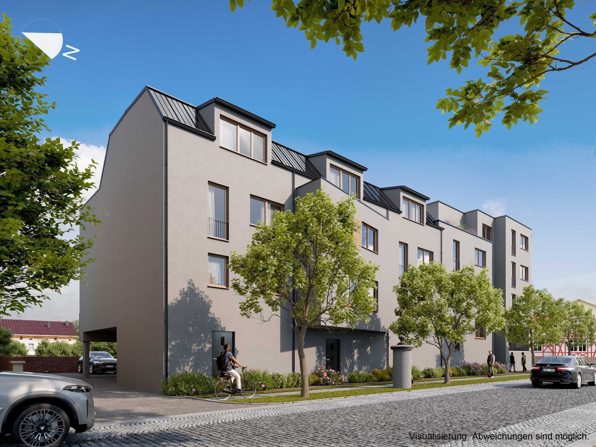 Modernes Mehrfamilienhaus mit Balkonen, Bäumen und geparkten Autos in einer sonnigen Straße