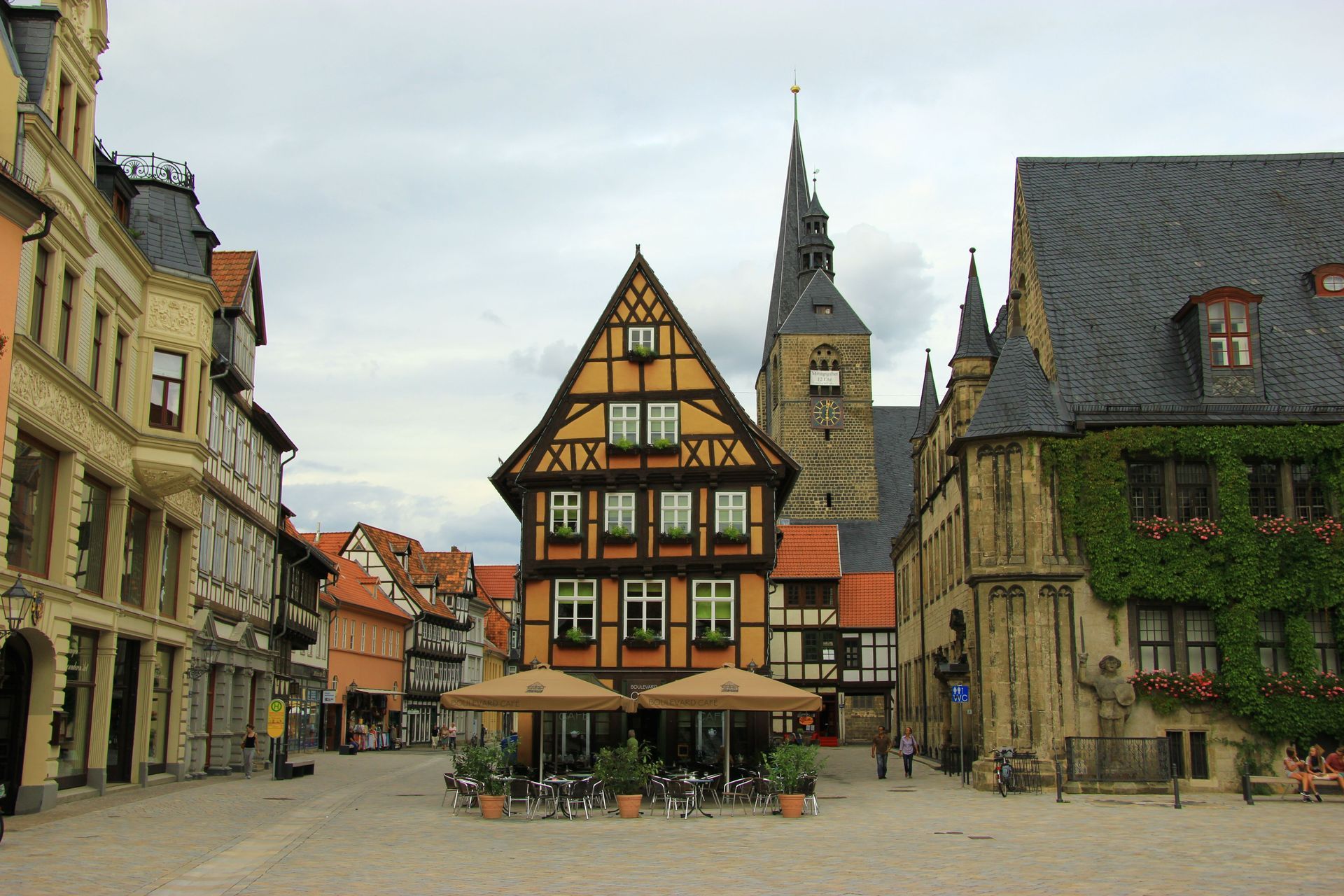 Historischer europäischer Marktplatz mit Fachwerkhäusern und einem Kirchturm unter bewölktem Himmel