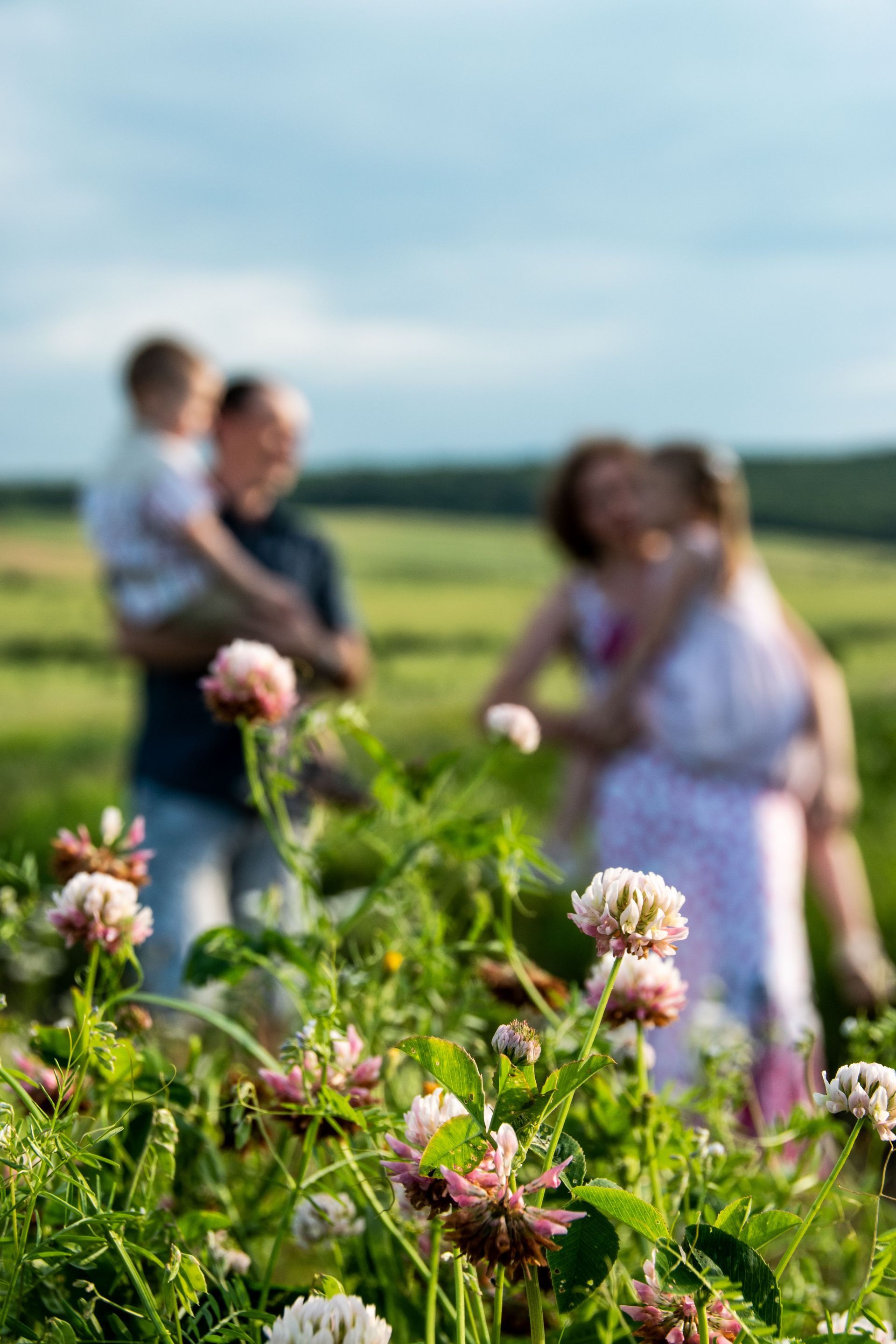 Menschen stehen auf einem Blumenfeld mit rosa Blüten, im Hintergrund unscharf.